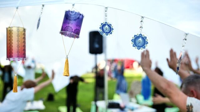 Decorative lanterns and spiritual symbols hanging above people practicing outdoor yoga in India