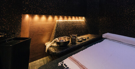 Modern hammam interior with stone massage table and copper accessories