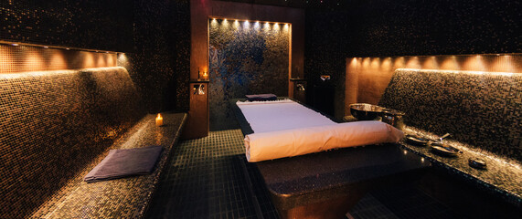 Modern hammam interior with stone massage table and copper accessories