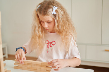 Young girl concentrating on building wooden blocks indoors