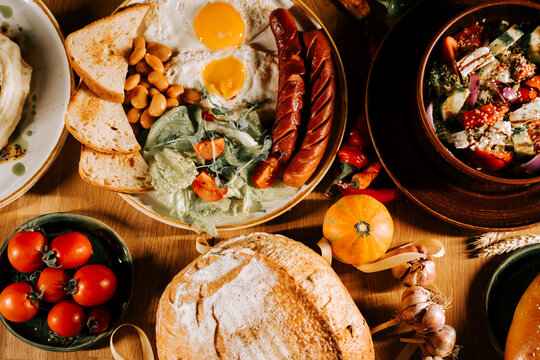Delicious breakfast spread with eggs, sausages, toast, and fresh vegetables on a wooden table