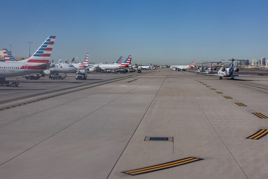 PHOENIX, ARIZONA, USA, NOVEMBER 09, 2025: A view through an airplane window of the tarmac at Phoenix Sky Harbor International Airport (PHX), showing several American Airlines aircraft parked at the ga