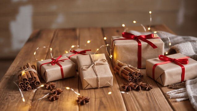 Rustic holiday scene with wooden table, wrapped presents, cinnamon sticks, and fairy lights, warm cozy tones - Powered by Adobe