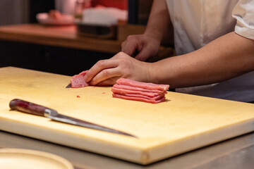 Chef slicing fresh meat on wooden cutting board in professional kitchen