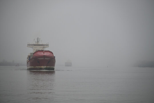 Vessels arrive at Hamburg Harbor on a foggy day. Crane, Vessel, River, Water. Hamburg Harbor, Hamburg, Germany - Powered by Adobe