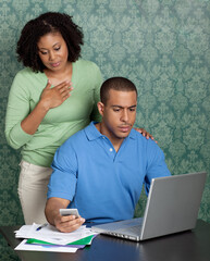 Obraz premium Young couple paying bills by using online banking at home