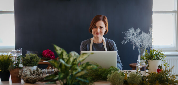 Smiling female florist working in her small flower shop.