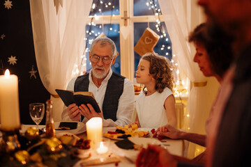 Grandparents reading from bible during Christmas dinner.