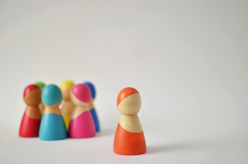 Orange wooden figure standing apart from colorful group