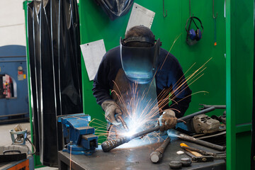 Artisan welder performing arc welding work in workshop