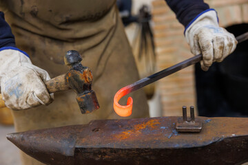 Artisan forging hot iron on anvil in workshop