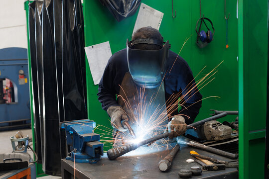 Artisan welder performing arc welding work in workshop - Powered by Adobe