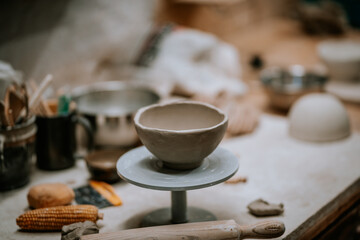 Ceramic bowl on a pottery wheel, surrounded by tools and materials, showcasing the artistry of pottery making in a creative workshop environment with natural lighting