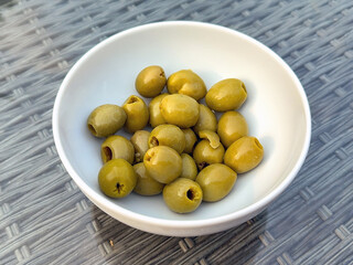 Close up view of a bowl of fresh green olives on a garden table
