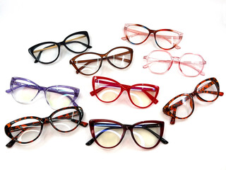Selection of women's glasses frames in different colours oand shapes n a plain white backgrond. Copy space.