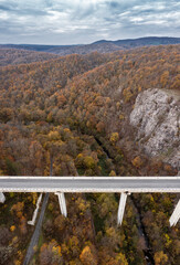 Aerial view of bridge of highway over the river in the mountain at autumn