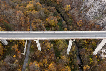 Aerial view of bridge of highway over the river in the mountain at autumn