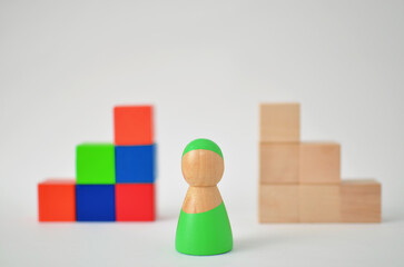 Wooden figure making a choice between colorful and plain blocks