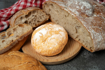 Rustic loaves of homemade bread and small rolls with a red checkered napkin