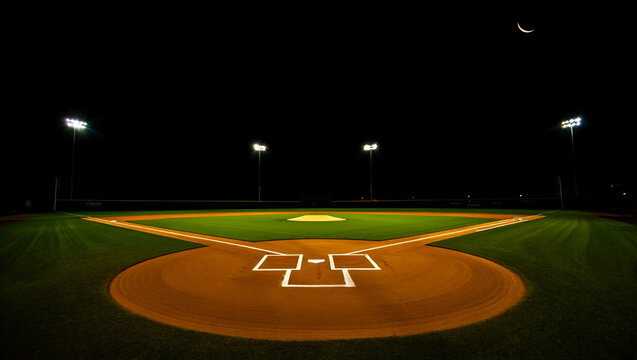 Illuminated baseball field under crescent moon night lights