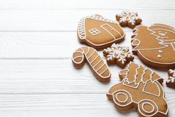 Tasty gingerbread cookies on white wooden table, closeup. Space for text
