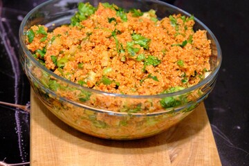 An image of kısır made with homemade bulgur in a glass bowl. Lettuce, green onions, and parsley are added to the kısır. Traditional Turkish food. Vegan diet. Snack plate.