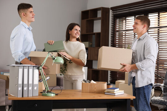 Moving day. Group of workers packing different belongings into boxes in office