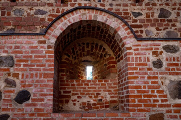 close-up view of a brick wall featuring an arched niche and a small, narrow opening within it.