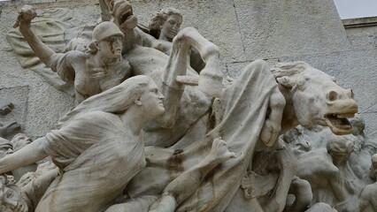 Rome, Italy – 11 January 2025. Scene from the Mazzini monument with a straining horse, soldier in helmet mid-action, and a woman extending her arm as figures surge ahead in carved movement.