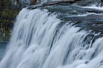 The sweeping river tumbles over the edge, sending spray into the crisp mountain air.