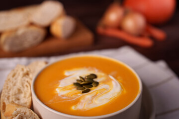 creamy pumpkin soup with toasted bread and pumpkin seeds in a cozy kitchen setting featuring rich autumnal hues and rustic ingredients on a wooden table, nurturing, decadent, baked, nourishing