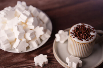 a cozy cup of hot chocolate topped with chocolate sprinkles and surrounded by snowflake-shaped marshmallows on a wooden table, creating a warm and inviting winter treat scene, gather, relaxation