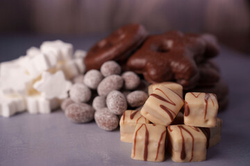 assortment of decorative cookies and confections featuring chocolate drizzles, white marshmallows, powdered treats set against soft blurred background creating festive atmosphere, flavors
