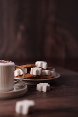 cozy scene of hot coffee with cookies and marshmallows against a warm wooden backdrop evoking a sense of comfort and indulgence, dark, grains, graceful, aesthetic, composed, artful, crafted