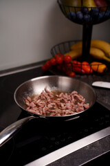 sizzling bacon strips frying in skillet next to vibrant fresh produce including cherry tomatoes, bananas, and peppers on modern kitchen countertop, delicious, preparation, simmer, slice, homey