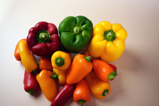 vibrant array of colorful bell peppers arranged on a light surface highlighting freshness and variety in red, green, yellow, and orange hues for a joyful culinary display, contrast, topview, ripe