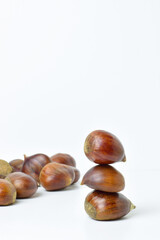 Close up, chestnuts stacked on a white background. In vertical.