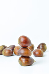 Close up, chestnuts stacked on a white background. In vertical.