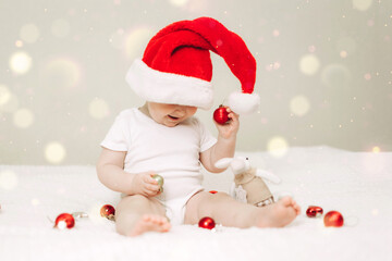 Baby in Santa Hat Holding Ornaments on White Blanket