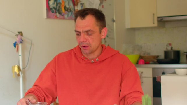 Male sample critic in cozy kitchen environment, Individual expressing opinions on drink amidst relaxed