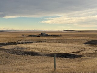 Obraz premium Deserted rural farm with broken fence lines, empty fields and signs of long-term neglect across the landscape. Gleichen, Alberta, Canada. Long Lost Land. Cinematic atmosphere.
