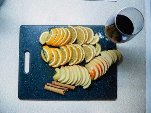 sliced apple, cinnamon sticks and anise on a white plate with wine on the table