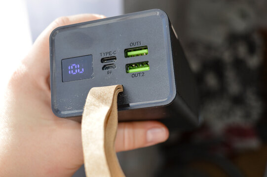 portable power bank with digital display and USB ports held in hand, concept of mobile charging, modern technology, portable energy source, and electronic device for everyday use and travel.