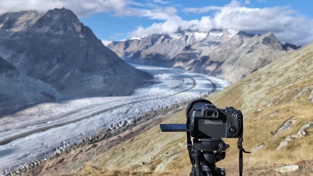 Professional camera on a tripod filming glacier in Swiss alps, Aletsch glacier