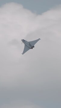 Fast fighter jet during high speed combat maneuvers with clouds