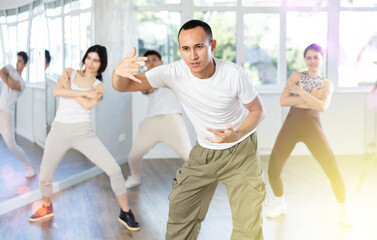 Guy, together with dance youth group, rehearses performance, works out succession of events movements execution of dancing show, modern energetic dances.