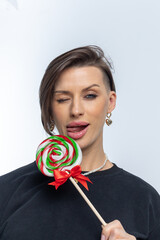 Portrait of beautiful woman with sweets round lollipop in her hand. Vertical photo.