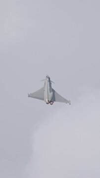 Fast fighter jet during high speed combat maneuvers with clouds