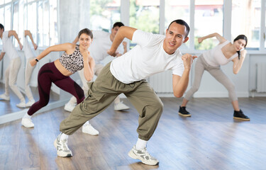 Guy repeats and teaches sequences of movements and actions during dance lesson, trains to perform...