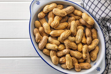 Peanuts in shell. Groundnuts in bowl on white table. Top view.